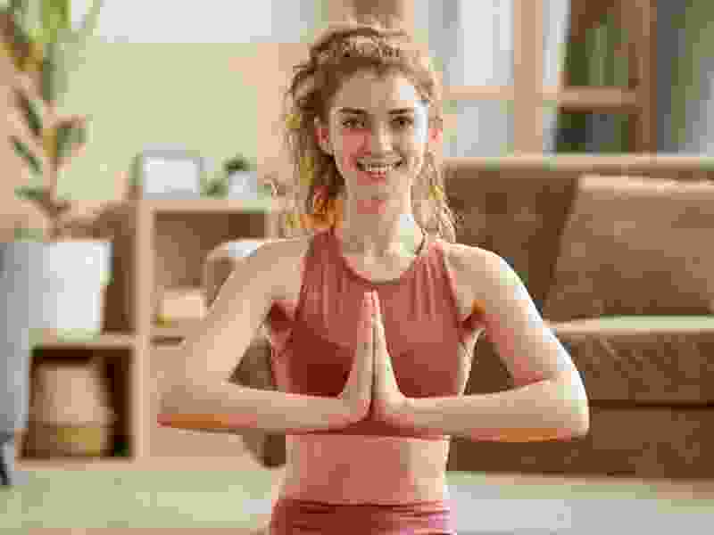 Smiling woman in a yoga pose with palms pressed together